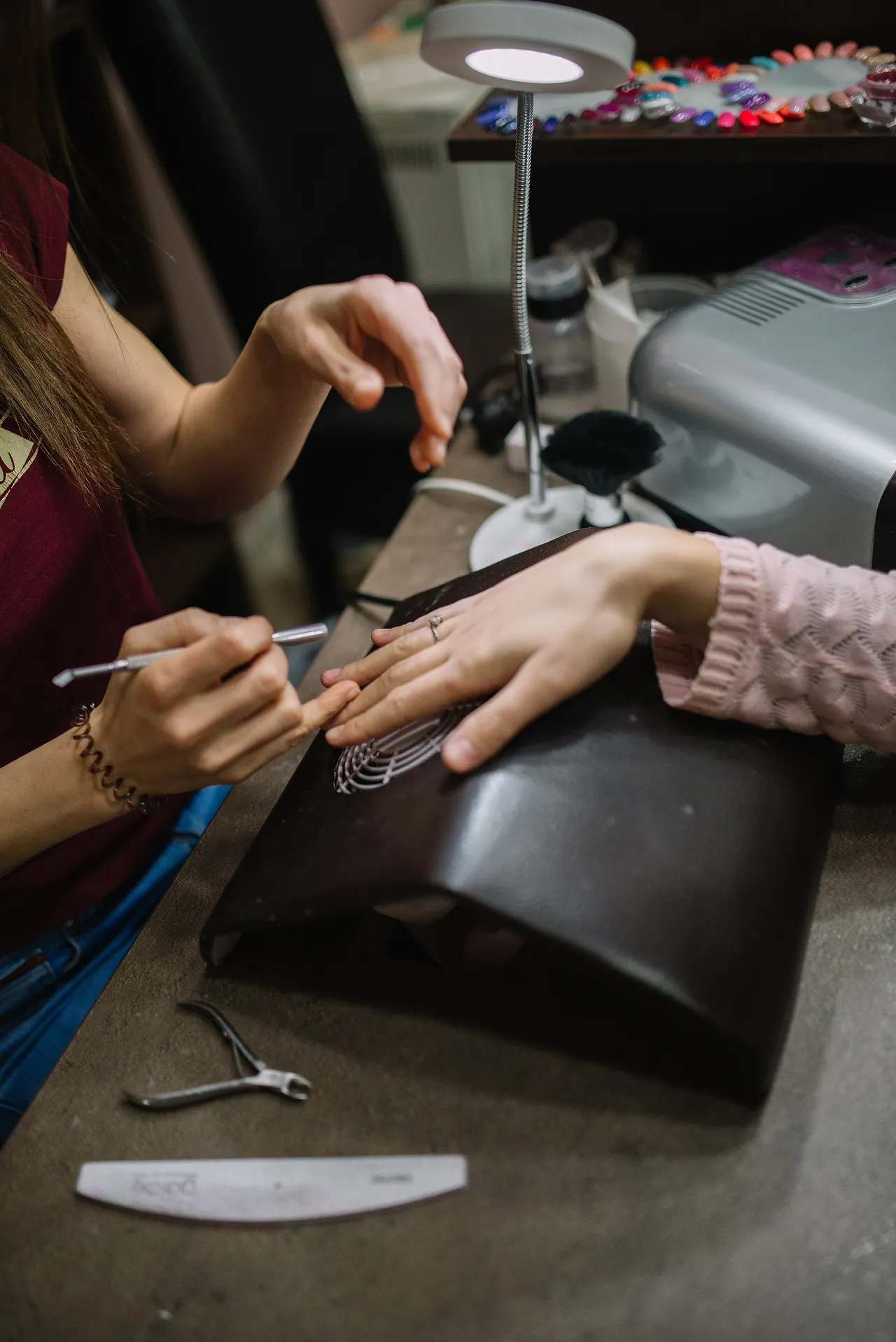 Técnica de uñas aplicando un diseño de manicura a una clienta